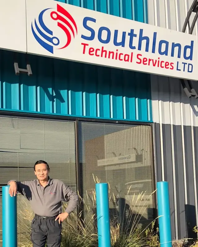 The owner of Southland Technical Services standing beside the company sign